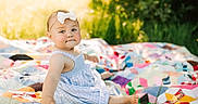 Layken joined the competition — help win amazing prizes! baby, bow, child, colorful, cute, daylight, dress, girl, grass, happy, headband, infant, nature, outdoor, patchwork, portrait, quilt, sitting, smile, sunlight