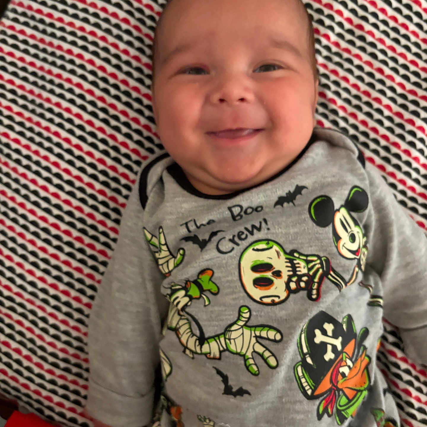 Bobby Ray Coca Iii is registered to the contest to win money with this photo: baby, bats, cartoon_characters, child, clothing, cute, face, halloween, happy, indoor, infant, lying_down, mickey_mouse, onesie, patterned_blanket, pirate, portrait, skeleton, smiling, young