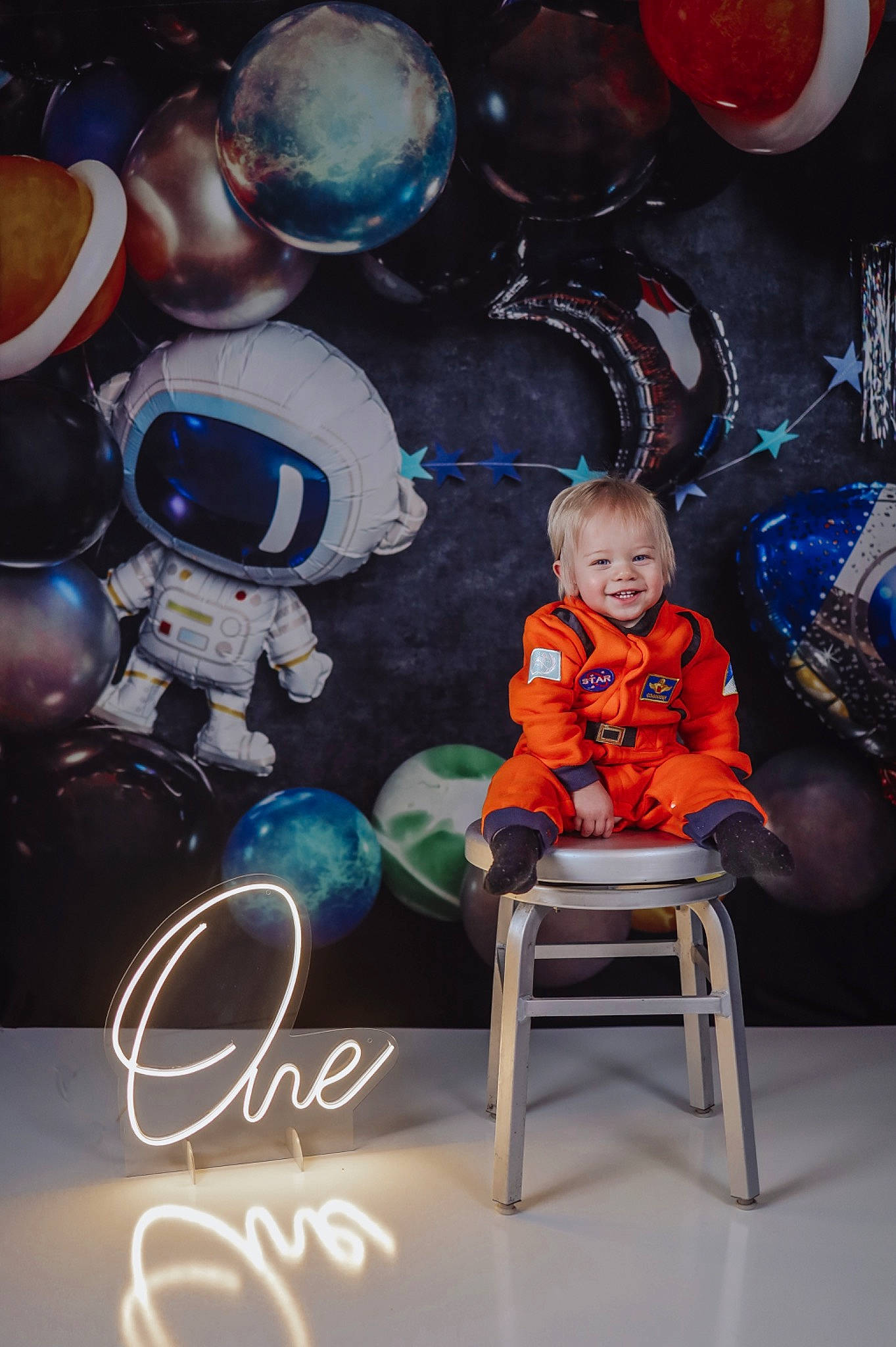 Nolan is registered to the contest to win money with this photo: art, astronaut, astronomical_object, balloon, chair, child, electric_blue, event, flash_photography, font, fun, graphic_design, illustration, joy, person, personal_protective_equipment, sitting, smile, space, t_shirt