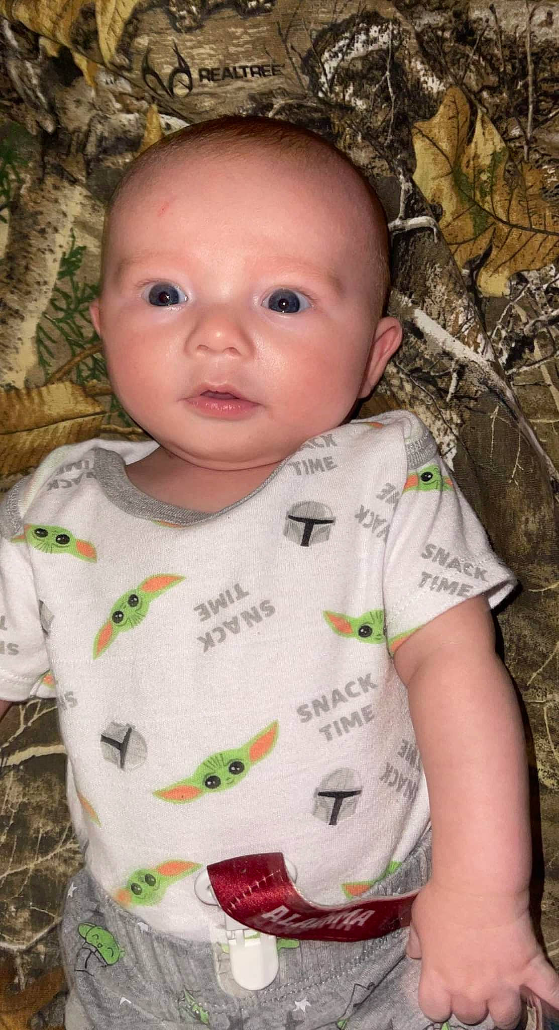 Abel is registered to the contest to win money with this photo: baby, baby_toddler_clothing, cheek, child, chin, collar, eye, eyelash, grass, happy, head, iris, leaf, lip, nose, pattern, person, skin, sleeve, toddler