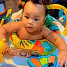 baby, child, bantu_knots, activity_center, toy, colorful, phone_case, curious, indoor, playtime, infant, portrait, smiling, cute, hands, face, bright_colors, young_child, engaged, expression