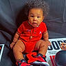 afro, baby, balloons, basketball, black_background, celebration, child, curious, cute, decor, indoor, michael_jordan, necklace, person, portrait, poster, red_clothing, sitting, sneakers, sports_theme