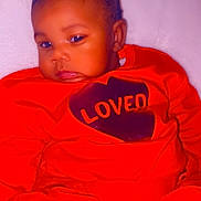 Naomi is registered to the contest to win money with this photo: baby, child, red_clothing, heart, bow, couch, indoor, portrait, cute, infant, sitting, love, cozy, person, young_child, face, expression, homedecor, relaxing, comfort