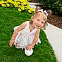 ball, child, cute, daylight, dress, flowers, girl, grass, greenery, hair_bows, happy, nature, outdoor, playful, portrait, sidewalk, smiling, toddler, white_dress, yellow_flowers