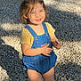 blue_eyes, car, casual_clothing, child, cute, daylight, denim_overalls, gravel, happy, outdoor, person, sandals, shadow, short_hair, small_child, smiling, standing, sunlight, toddler, yellow_shirt