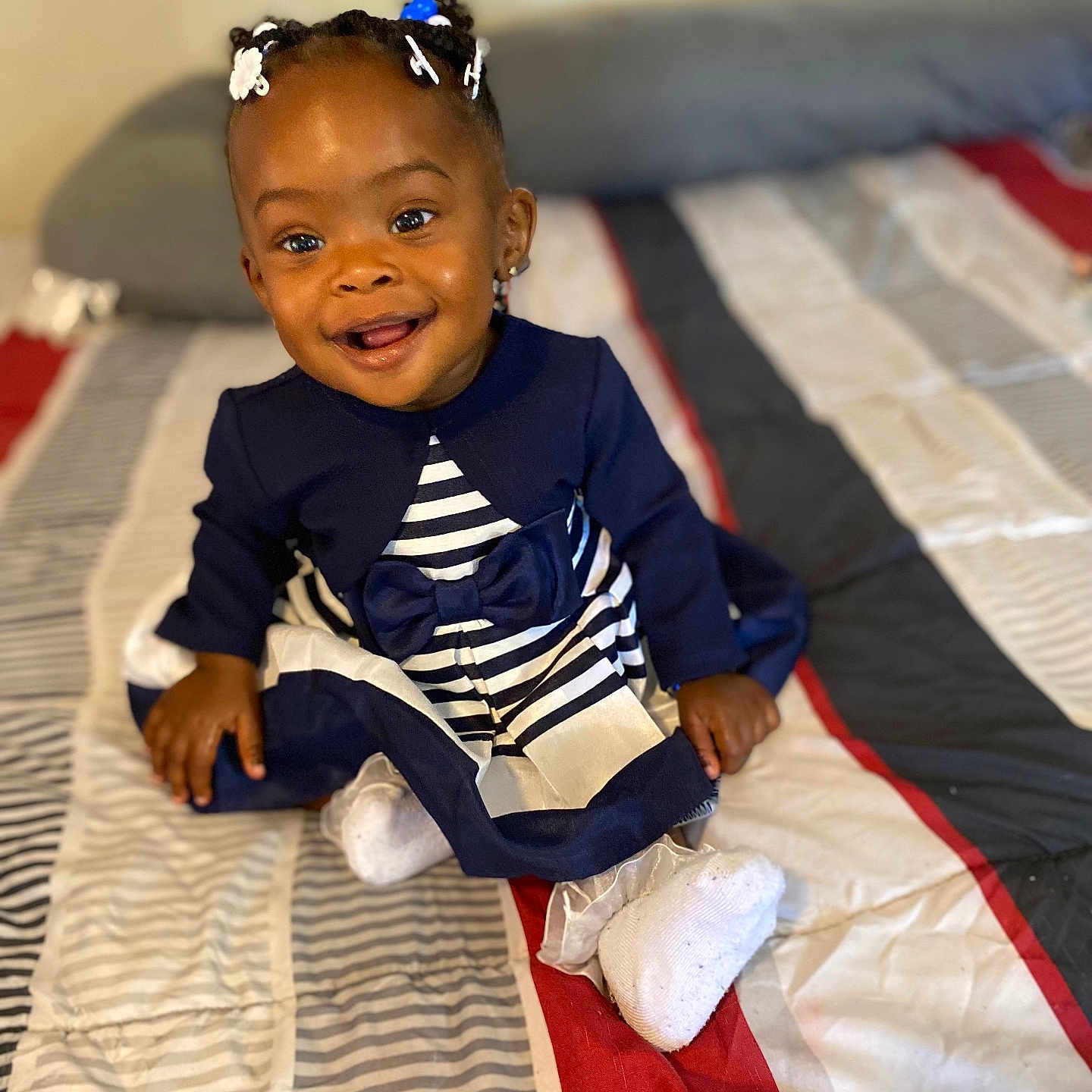 Riley Easter is registered to the contest to win money with this photo: baby, babylaughing, bed, bedroom, clothing, couch, cushion, dress, face, flag, furniture, happy, head, indoors, person, photography, portrait, room, sitting, smile