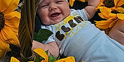Elena is registered to the contest to win money with this photo: baby, smiling, sunflower, basket, flower, outdoor, headband, happy, child, nature, greenery, white_clothing, cute, infant, summer, plant, portrait, skin, grass, leaf
