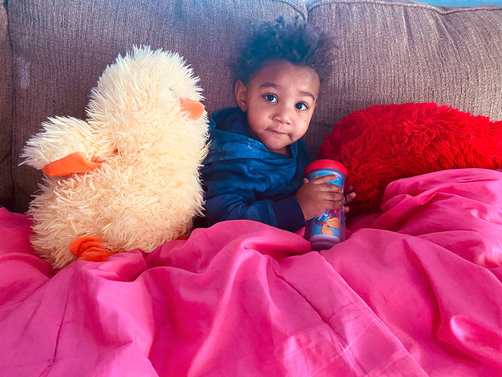 Lucius is registered to the contest to win money with this photo: baby, baby_toddler_clothing, beauty, comfort, couch, facial_expression, finger, fun, happy, linens, magenta, mammal, person, pink, product, red, skin, textile, toddler, toy