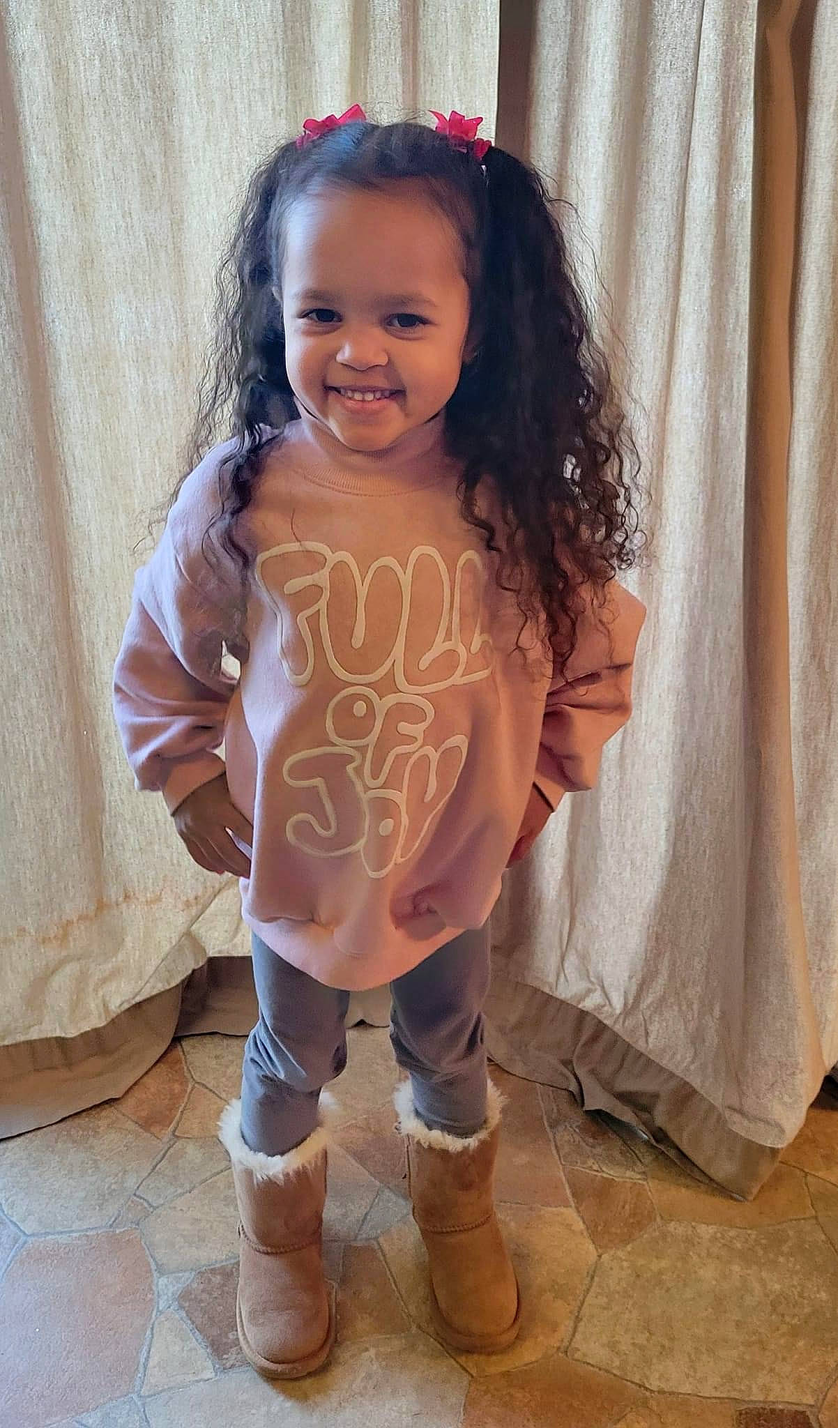 Zariah is registered to the contest to win money with this photo: arm, baby_toddler_clothing, child, curtain, face, finger, flooring, hand, happy, human_body, joy, knee, person, pink, shorts, skin, smile, standing, textile, thigh