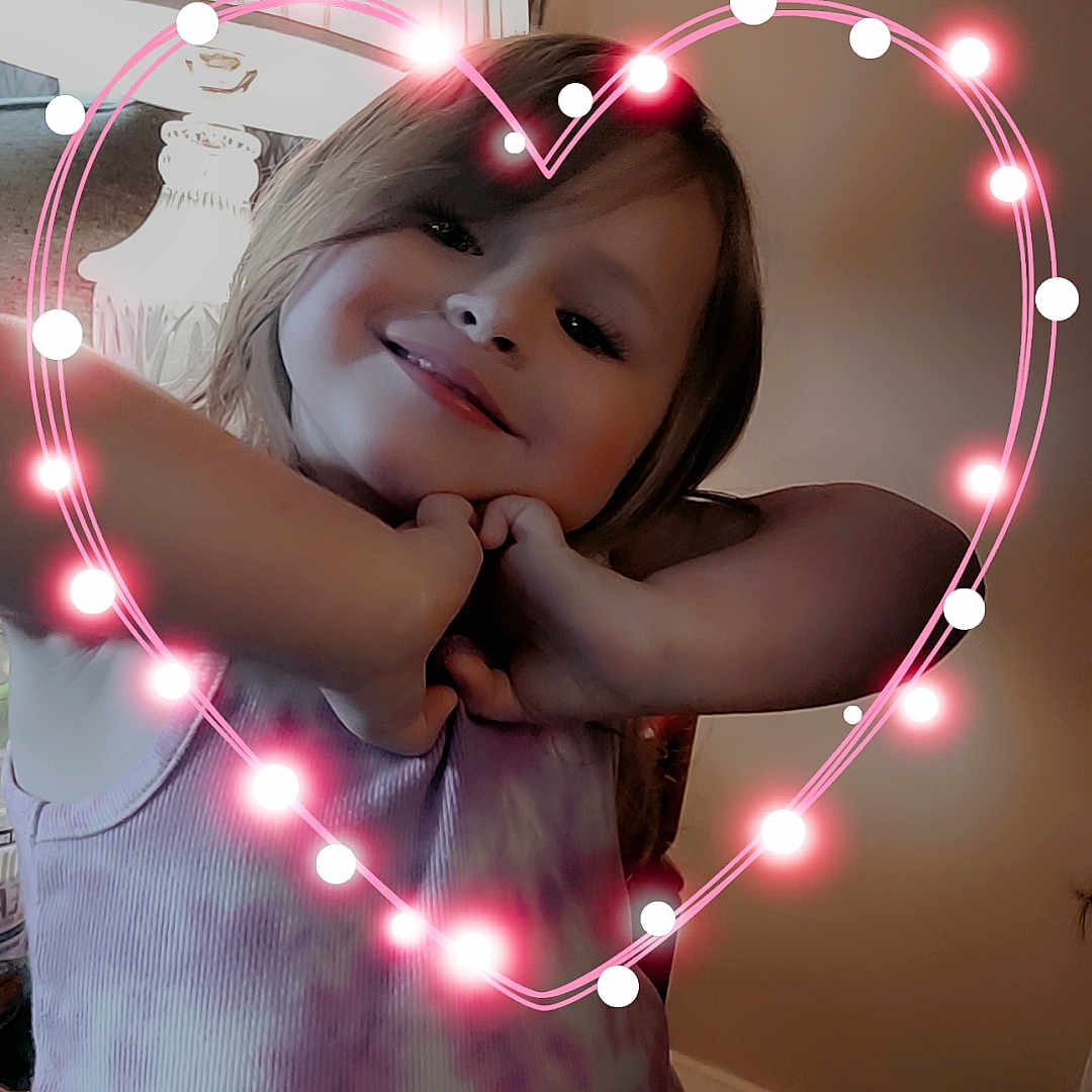 Sophia is registered to the contest to win money with this photo: accessories, baby, bodypart, electronics, face, finger, flare, hand, happy, head, heart, indoors, light, lighting, mouth, pattern, person, photography, portrait, smile