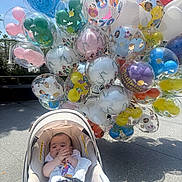Valentino joined the competition — help win amazing prizes! baby, car_seat, balloons, outdoor, sunny, cartoon_characters, colorful, child, infant, sidewalk, shade, happy, toy, mickey_mouse, disney, footwear, clothing, person, celebration, festive