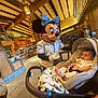 Valentino joined the competition — help win amazing prizes! baby, stroller, car_seat, child, character_costume, minnie_mouse, restaurant, indoor, person, smile, blanket, table, mask, people, wooden_beams, lighting, floor, clothing, happy, entertainment