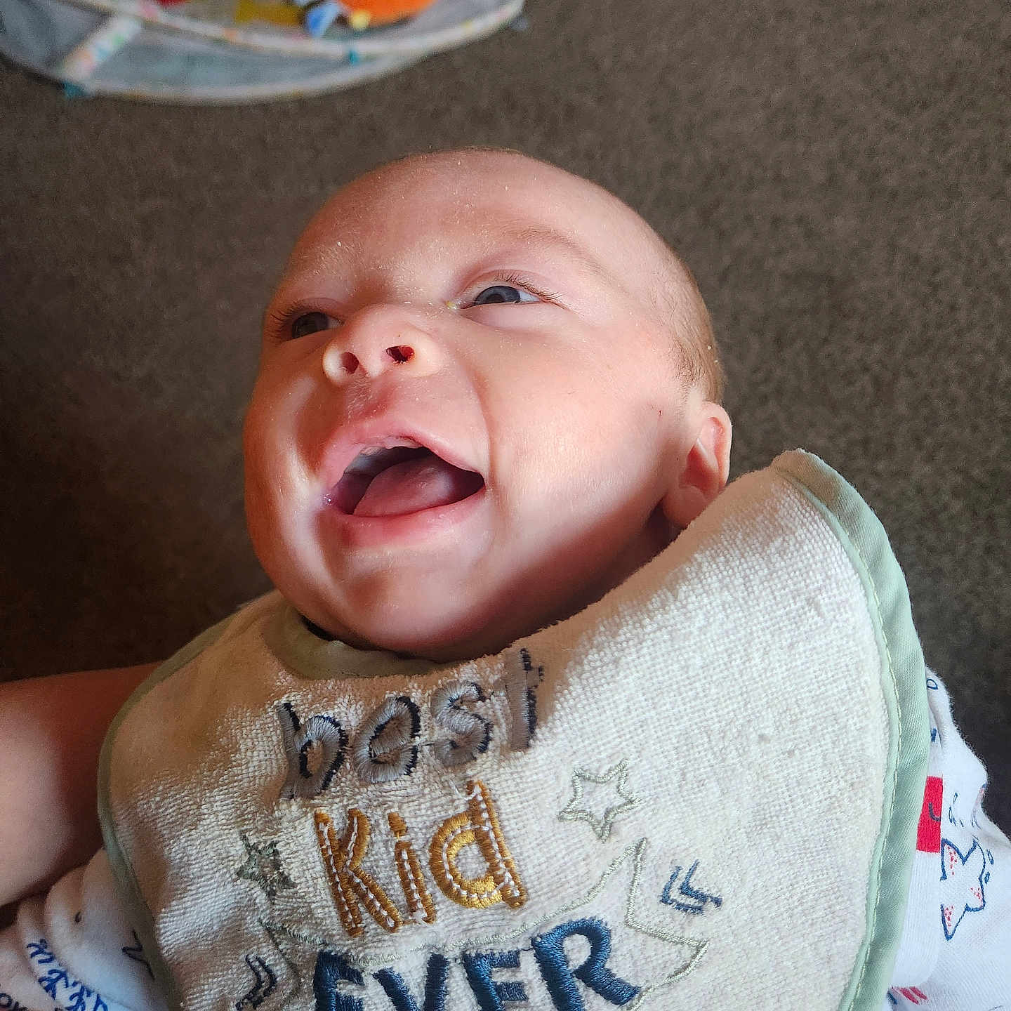 Dawson joined the competition — help win amazing prizes! baby, smile, bib, indoor, happy, child, face, clothing, toy, background, carpet, infant, cute, person, young, joyful, expression, closeup, apparel, fabric