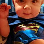 Calvin joined the competition — help win amazing prizes! baby, superman, costume, child, portrait, closeup, cityscape, building, blue, red, yellow, cape, face, eyes, skin, hand, leg, indoor, cute, superhero