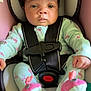 baby, infant, car_seat, seat_belt, pajamas, flamingo_pattern, booties, child, cute, indoors, strapped_in, person, face, black_hair, serious_expression, sitting, soft_toys, car_safety, close_up, newborn