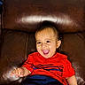 toddler, child, smiling, happy, laughing, red_shirt, navy_shorts, leather_couch, indoor, portrait, cute, baby, sitting, young_child, joy, expression, person, head, face, casual_clothing