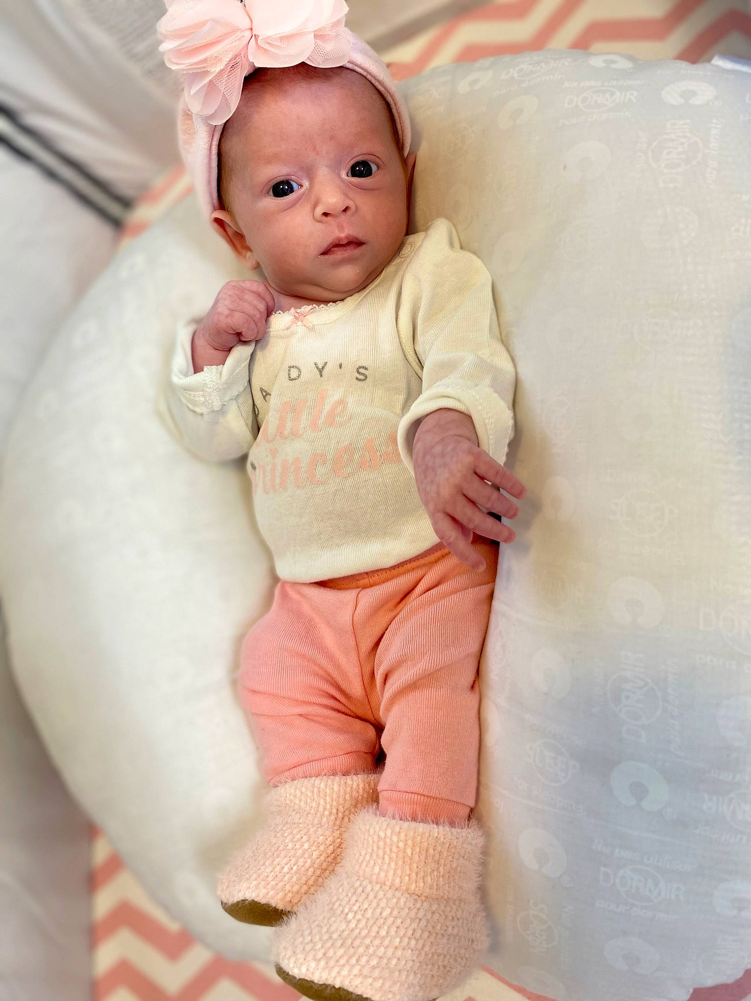 Laila is registered to the contest to win money with this photo: abdomen, baby, baby_products, baby_toddler_clothing, baby_toys, cheek, child, comfort, happy, human_body, linens, neck, peach, person, pink, sitting, skin, sleeve, sock, t_shirt
