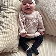 Alia a rejoint le concours — aidez-le/la à gagner de superbes lots ! baby, child, smiling, sweater, bow, leggings, socks, cushion, pillow, cozy, soft, indoors, cute, infant, comfortable, seated, portrait, happy, fashion, person