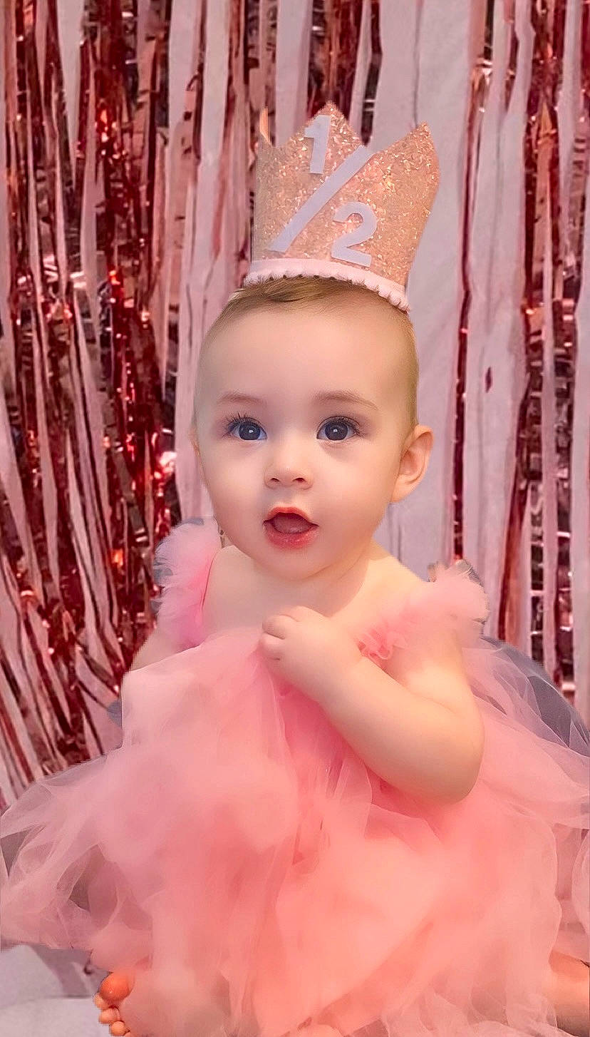 Natalie is registered to the contest to win money with this photo: bridal_accessory, costume_hat, dress, event, fashion_design, fun, hair_accessory, happy, head, headgear, headpiece, human_body, jewellery, magenta, party_hat, party_supply, peach, person, pink, toddler