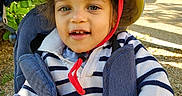 Nohan a rejoint le concours — aidez-le/la à gagner de superbes lots ! baby, blue_pants, casual_clothing, child, daylight, face, happy, hat, nature, outdoor, portrait, red_strap, seatbelt, smiling, striped_sweater, stroller, sunlight, toddler, trees, young_child