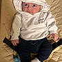 baby, hoodie, white_clothing, pacifier, infant, cute, child, sitting, blue_pants, white_socks, quilted_surface, indoor, looking_up, small_hands, face, expression, casual_clothing, soft_lighting, young_child, clothing