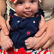 Evee is registered to the contest to win money with this photo: baby, child, infant, blue_eyes, bow, red_white_blue, stars, stripes, clothing, cute, tongue_out, hands, person, holding, pattern, skirt, sitting, portrait, smiling, closeup