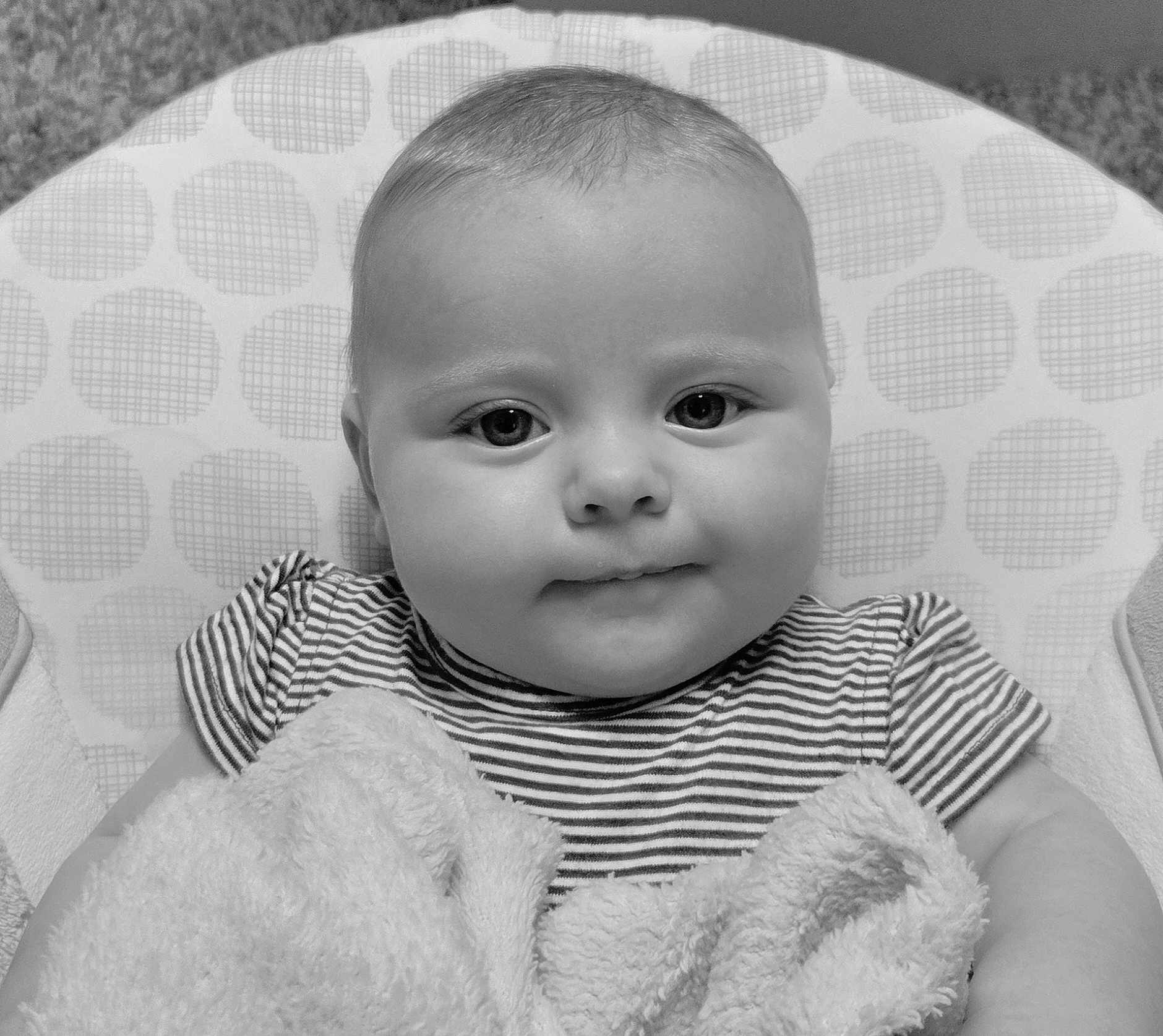 Evee joined the competition — help win amazing prizes! baby, infant, face, portrait, striped_shirt, blanket, cushion, polka_dots, black_and_white, closeup, child, cute, soft_texture, indoor, smiling, young, person, head, chubby_cheeks, seated