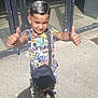 Younis a rejoint le concours — aidez-le/la à gagner de superbes lots ! child, boy, thumbs_up, colorful_clothing, shorts, sneakers, bag, hair, smile, outdoor, sunlight, shadow, concrete, glass_door, urban, standing, happy, casual, person, daylight