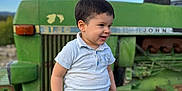 Kayden a rejoint le concours — aidez-le/la à gagner de superbes lots ! child, toddler, boy, jeans, white_polo, tractor, tire, outdoor, sky, green, smiling, portrait, farm, vehicle, dirt, casual_clothing, daylight, nature, happy, young