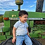 child, toddler, boy, jeans, white_polo, tractor, tire, outdoor, sky, green, smiling, portrait, farm, vehicle, dirt, casual_clothing, daylight, nature, happy, young