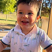 Kayden participe au concours pour gagner de l'argent avec cette photo : child, toddler, smiling, happy, outdoor, park, daylight, boy, shirt, polo_shirt, pattern, dog_print, cute, face, portrait, short_hair, sunlight, playground, nature, casual_clothing