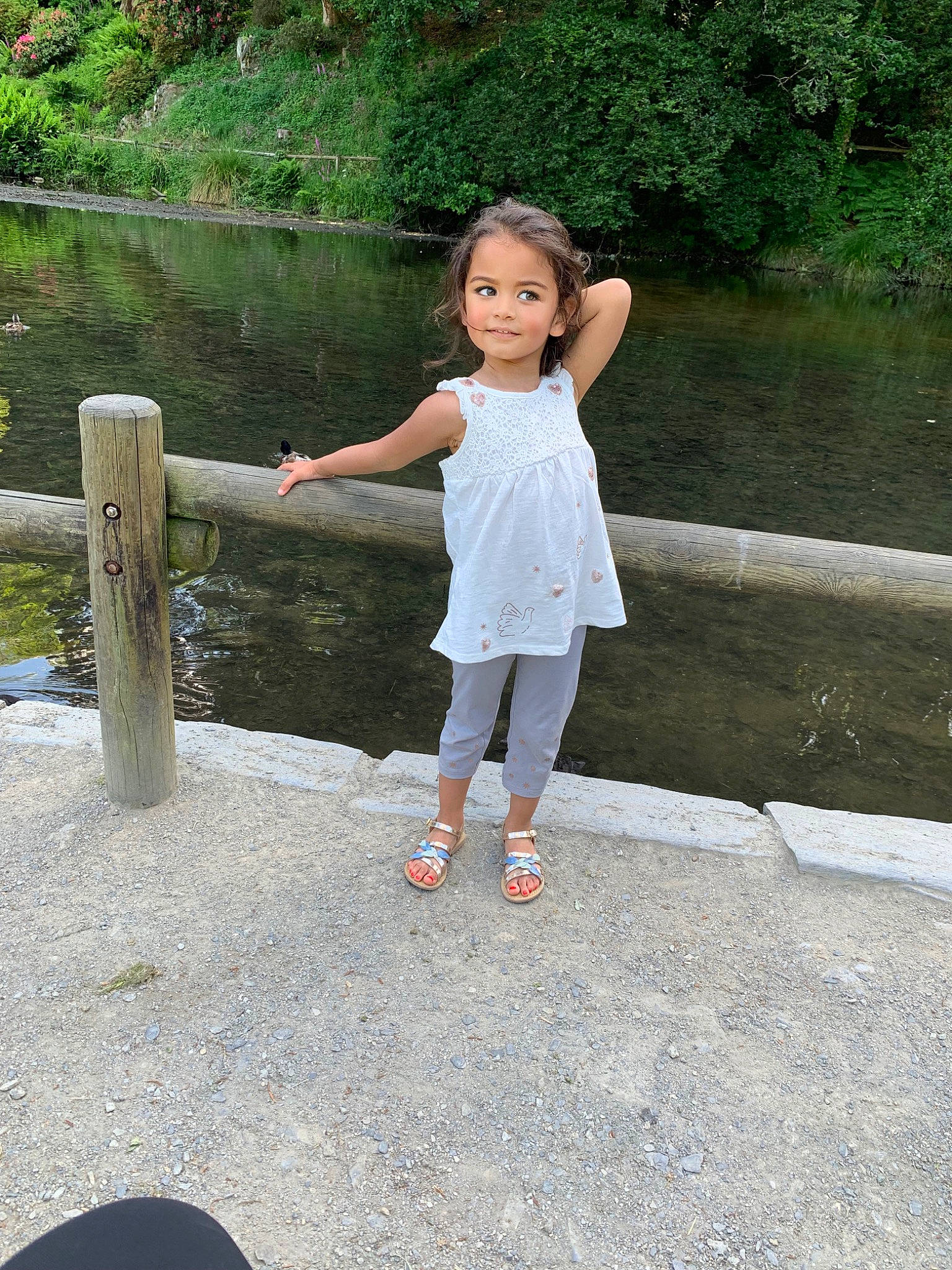 Louisa participe au concours pour gagner de l'argent avec cette photo : bank, child, foot, fun, garden, gesture, grass, happy, human_leg, joy, lake, leg, leisure, people_in_nature, person, plant, recreation, sitting, toddler, tree
