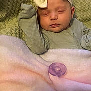 Ember is registered to the contest to win money with this photo: baby, sleeping, headband, bow, blanket, pacifier, green, pink, cozy, infant, closeup, portrait, soft, cute, child, resting, indoors, textured_background, clothing, peaceful