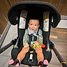 baby, infant, child, swing, toy, bee, pink_socks, floor, wooden_wall, tile_floor, clothing, smiling, indoor, seat, straps, footwear, person, cute, happy, portrait