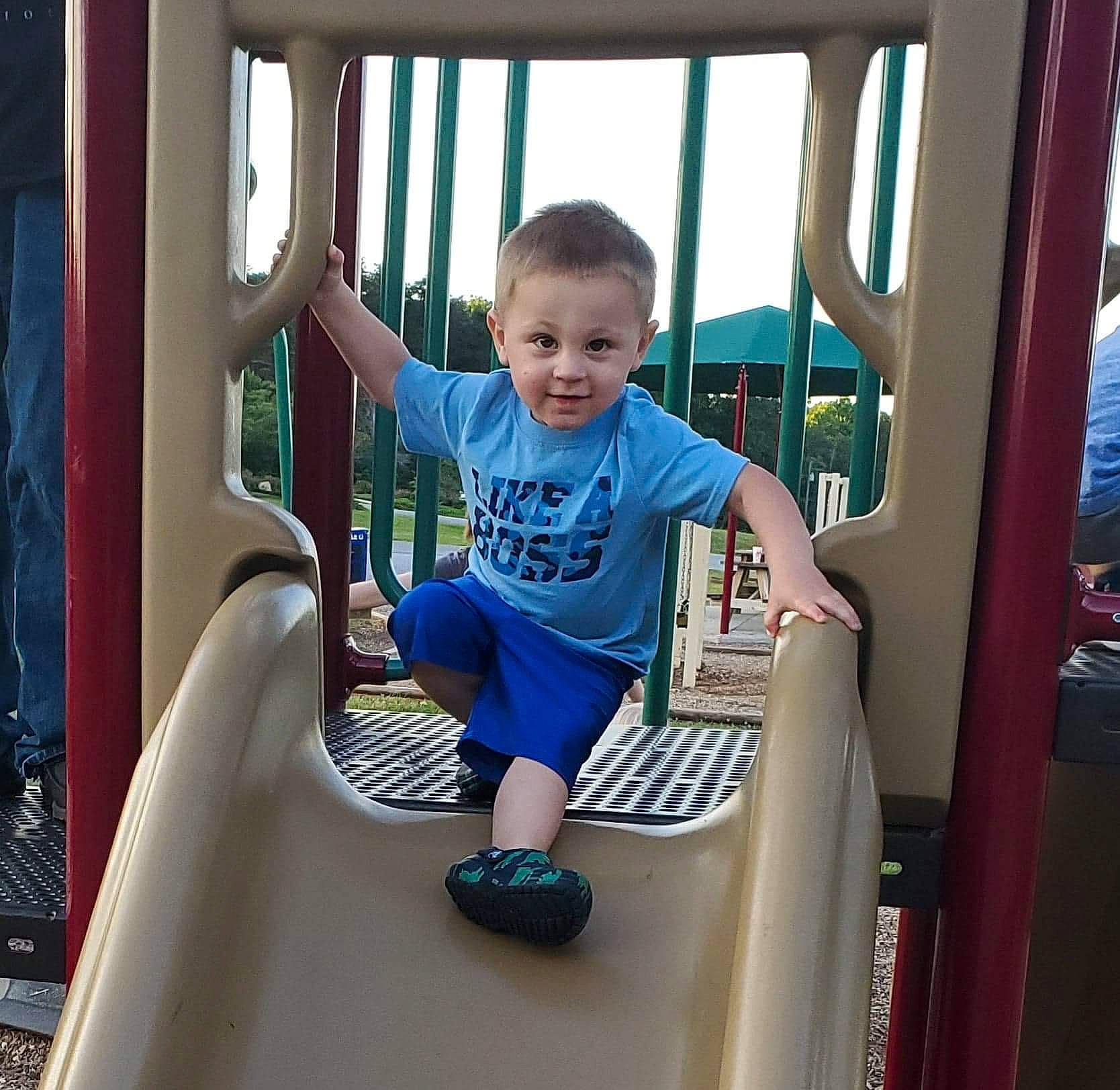 Daniel is registered to the contest to win money with this photo: baby_toddler_clothing, child, chute, city, electric_blue, fun, happy, joy, leisure, outdoor_play_equipment, person, play, playground, playground_slide, recreation, shorts, sky, smile, standing, summer