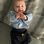 Léo a rejoint le concours — aidez-le/la à gagner de superbes lots ! baby, infant, child, person, clothing, shirt, pants, button, couch, blanket, furniture, hand, face, eyes, smile, indoor, cozy, reaching, cute, portrait