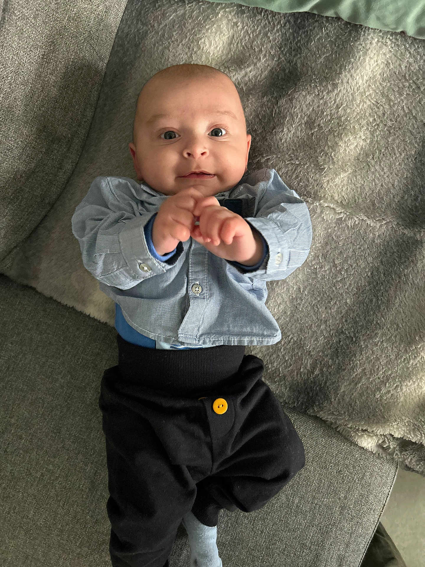 Léo a rejoint le concours — aidez-le/la à gagner de superbes lots ! baby, infant, child, person, clothing, shirt, pants, button, couch, blanket, furniture, hand, face, eyes, smile, indoor, cozy, reaching, cute, portrait