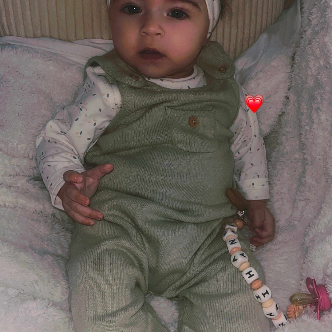Raihanna a rejoint le concours — aidez-le/la à gagner de superbes lots ! baby, blanket, child, clothing, comfort, cozy, cute, expression, face, green_overalls, headband, indoor, infant, pacifier, portrait, seated, soft_texture, toy, white_shoes, young