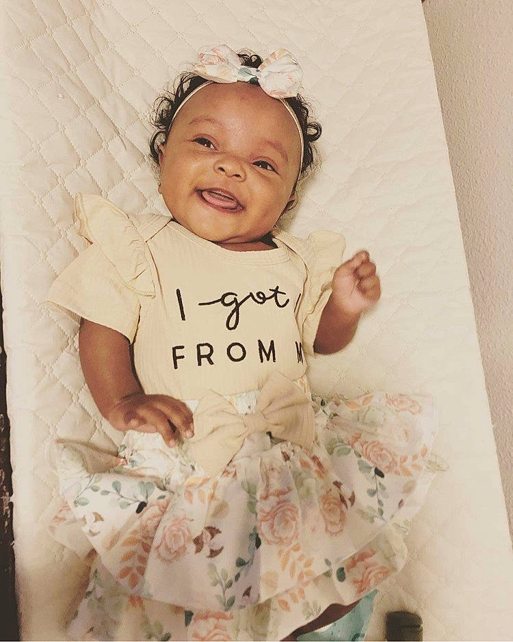 Amaia is registered to the contest to win money with this photo: baby, baby_products, baby_toddler_clothing, child, clothing, fashion_accessory, hair_accessory, happy, headband, headpiece, linens, pattern, peach, person, pink, sitting, sleeve, smile, t_shirt, textile