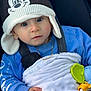 baby, child, hat, blue_sweater, blanket, stroller, toy, hand, face, cute, infant, warm_clothing, chain_necklace, outdoor, portrait, young_child, cartoon_hat, comfort, closeup, expression