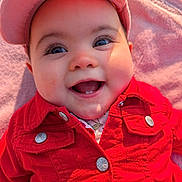 élaïa participe au concours pour gagner de l'argent avec cette photo : baby, smiling, red_jacket, cap, blanket, outdoor, happy, face, child, infant, portrait, cute, clothing, button, cheeks, sunlight, closeup, person, headwear, warm