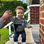 Kyrie joined the competition — help win amazing prizes! baby, blue_sky, brick_wall, casual_clothing, child, curly_hair, daylight, greenery, hand_holding, happy, hoodie, jeans, outdoor, person, porch, smiling, support, toddler, walking, white_sneakers