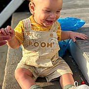Kyrie joined the competition — help win amazing prizes! toddler, child, laughing, overalls, pooh, yellow_shirt, sneakers, socks, earring, outdoor, sunlight, concrete, hand_holding, smile, curly_hair, person, footwear, baby, sitting, happy