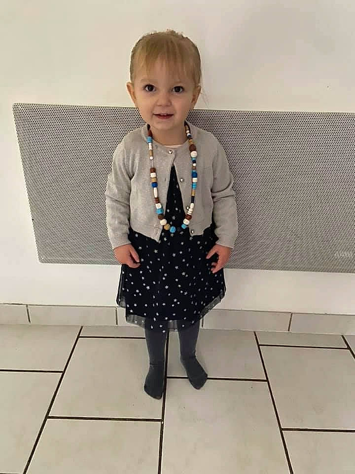 Mylène participe au concours pour gagner de l'argent avec cette photo : baby_toddler_clothing, day_dress, electric_blue, face, fashion_accessory, fashion_design, flooring, formal_wear, head, human_body, human_leg, knee, pattern, person, rectangle, sleeve, smile, street_fashion, thigh, toddler