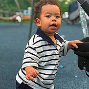 Noah joined the competition — help win amazing prizes! bokeh, boy, candid, child, curly_hair, daylight, face, family, hands, open_mouth, outdoor, play_equipment, playground, portrait, shorts, smiling, standing, striped_shirt, stroller, toddler