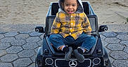 Noah is registered to the contest to win money with this photo: beach, child, happy, hood, mercedes_logo, outdoor, pavement, plaid_shirt, playful, portrait, sand, seaside, shoreline, sitting, smiling, sunlight, toddler, toy_car, water, yellow_clothing