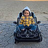 beach, child, happy, hood, mercedes_logo, outdoor, pavement, plaid_shirt, playful, portrait, sand, seaside, shoreline, sitting, smiling, sunlight, toddler, toy_car, water, yellow_clothing