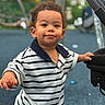 Noah joined the competition — help win amazing prizes! bokeh, brown_hair, child, clothing, curly_hair, daylight, eyes, face, hands, happy, outdoor, person, play, playground, portrait, smiling, standing, striped_shirt, stroller, toddler