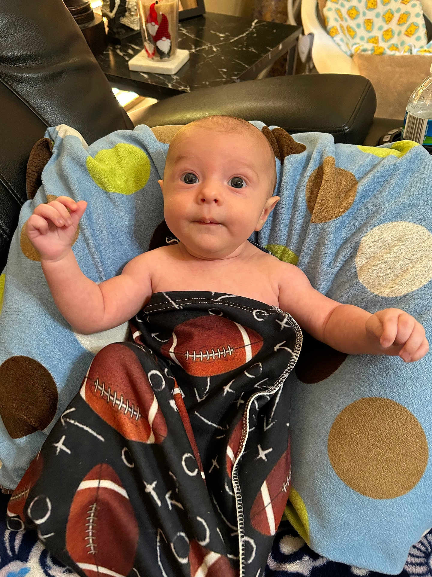 Caeson joined the competition — help win amazing prizes! baby, blanket, cushion, polka_dot, football, infant, person, indoor, furniture, leather_chair, curious, eyes, hand, face, head, pattern, soft, comfort, wrapped, lying