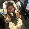 baby, infant, car_seat, child, cute, curly_hair, rainbow_pattern, clothing, seat_belt, indoors, portrait, young_child, baby_girl, sitting, child_seat, headrest, soft_lighting, expression, person, carrier